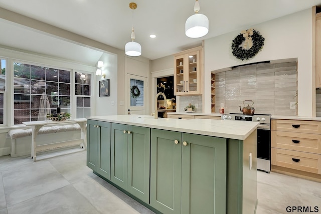 149 N 1st St, Seward, NE 68434 - kitchen featuring green cabinetry, stainless steel electric range, tasteful backsplash, an island with sink, and decorative light fixtures