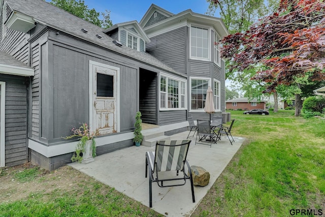 149 N 1st St, Seward, NE 68434 - back of house featuring a patio, a shingled roof, and a yard