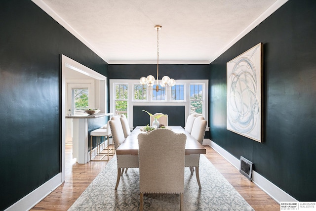 4427 Pine St, Omaha, NE 68105 - dining space featuring a chandelier, baseboards, wood finished floors, and crown molding