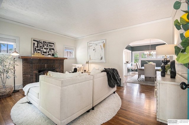4427 Pine St, Omaha, NE 68105 - living area with arched walkways, dark wood-type flooring, crown molding, a brick fireplace, and a chandelier