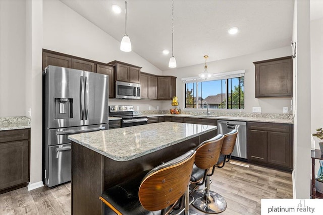 7784 N 88th Ave, Omaha, NE 68122 - kitchen with appliances with stainless steel finishes, dark brown cabinetry, vaulted ceiling, a center island, and light wood-style floors