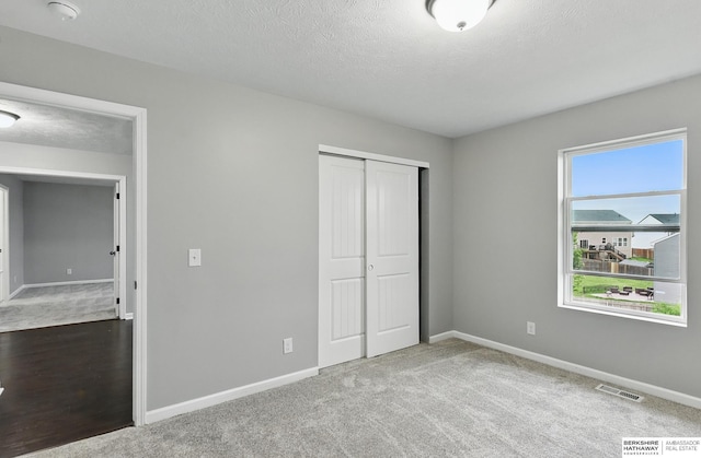8925 N 159th Ave, Bennington, NE 68007 - unfurnished bedroom featuring baseboards, carpet, a closet, and a textured ceiling