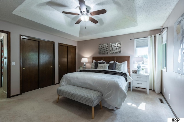15461 Harney St, Omaha, NE 68154 - bedroom with light colored carpet, a raised ceiling, multiple closets, a textured ceiling, and ceiling fan