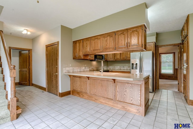 8240 Dorset Dr, Lincoln, NE 68510 - kitchen featuring stainless steel fridge with ice dispenser, a peninsula, light countertops, and light tile patterned flooring