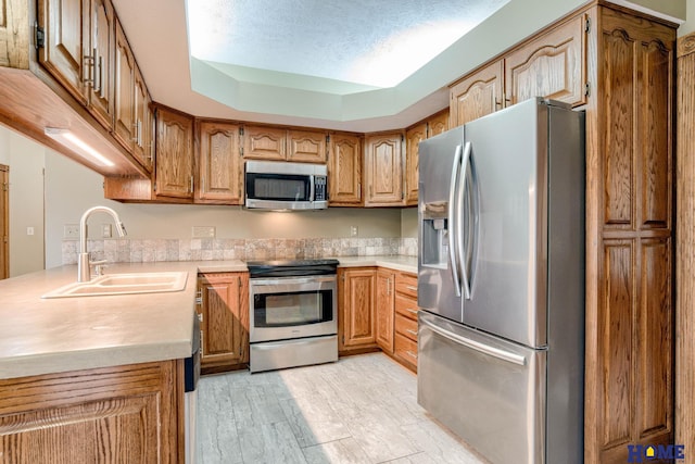 8240 Dorset Dr, Lincoln, NE 68510 - kitchen with stainless steel appliances, a sink, light countertops, light wood-style floors, and brown cabinetry