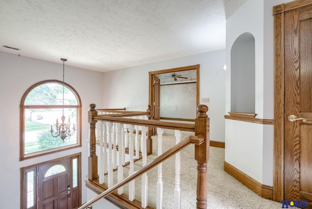 8240 Dorset Dr, Lincoln, NE 68510 - hall featuring a textured ceiling, a chandelier, carpet, baseboards, and arched walkways