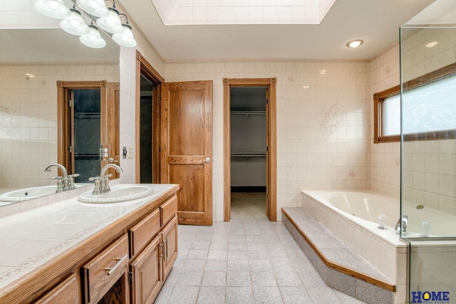 8240 Dorset Dr, Lincoln, NE 68510 - bathroom with vanity, a bath, tile walls, a skylight, and a walk in closet
