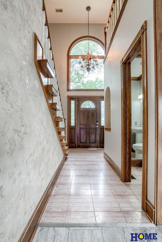 8240 Dorset Dr, Lincoln, NE 68510 - foyer featuring a chandelier, stairs, a towering ceiling, light tile patterned floors, and arched walkways