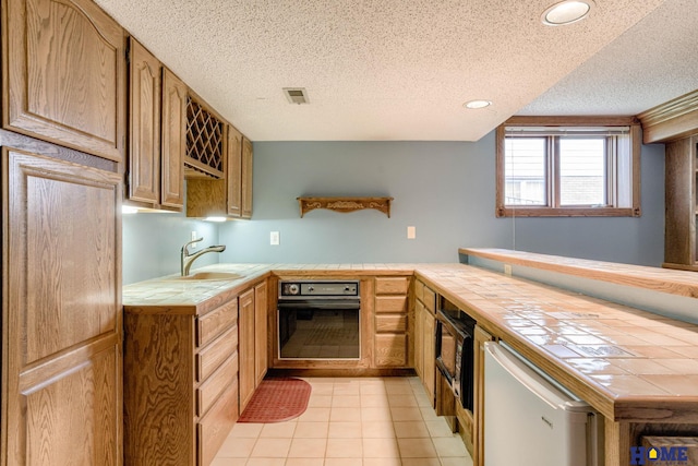 8240 Dorset Dr, Lincoln, NE 68510 - kitchen featuring tile countertops, black appliances, a sink, a textured ceiling, and light tile patterned floors
