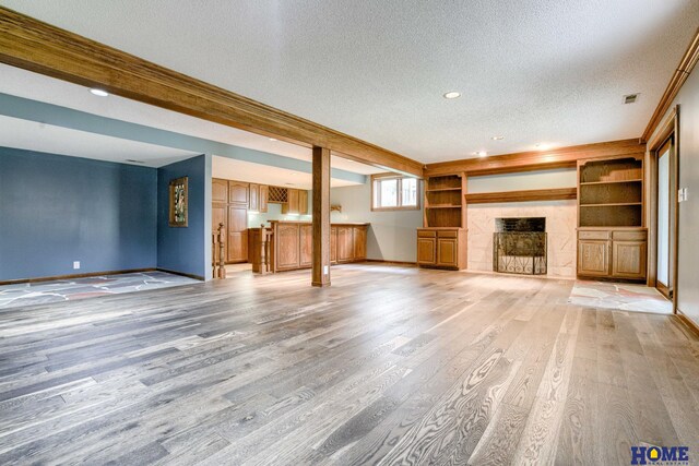 8240 Dorset Dr, Lincoln, NE 68510 - unfurnished living room with a textured ceiling, light wood-type flooring, baseboards, a tiled fireplace, and recessed lighting