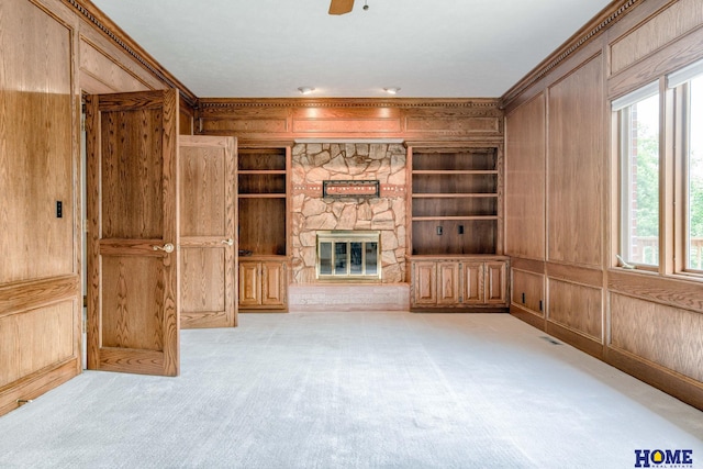 8240 Dorset Dr, Lincoln, NE 68510 - unfurnished living room featuring wood walls, light colored carpet, crown molding, a fireplace, and built in features