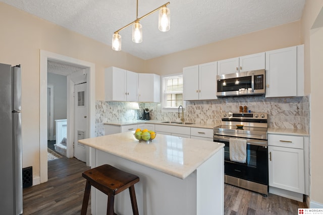 1512 N 41st Ave, Omaha, NE 68111 - kitchen featuring stainless steel appliances, a sink, a textured ceiling, dark wood-style flooring, and white cabinetry