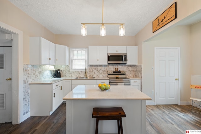 1512 N 41st Ave, Omaha, NE 68111 - kitchen with stainless steel appliances, a sink, dark wood finished floors, backsplash, and a textured ceiling