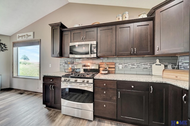 1309 Ridge Rd, Hickman, NE 68372 - kitchen with stainless steel appliances, vaulted ceiling, dark brown cabinetry, light wood-type flooring, and decorative backsplash