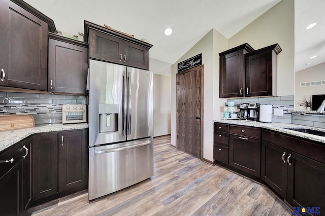 1309 Ridge Rd, Hickman, NE 68372 - kitchen with stainless steel refrigerator with ice dispenser, lofted ceiling, light wood-type flooring, backsplash, and dark brown cabinetry