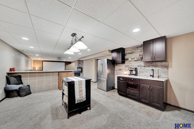 1309 Ridge Rd, Hickman, NE 68372 - kitchen with freestanding refrigerator, dark brown cabinets, light countertops, light colored carpet, and a drop ceiling
