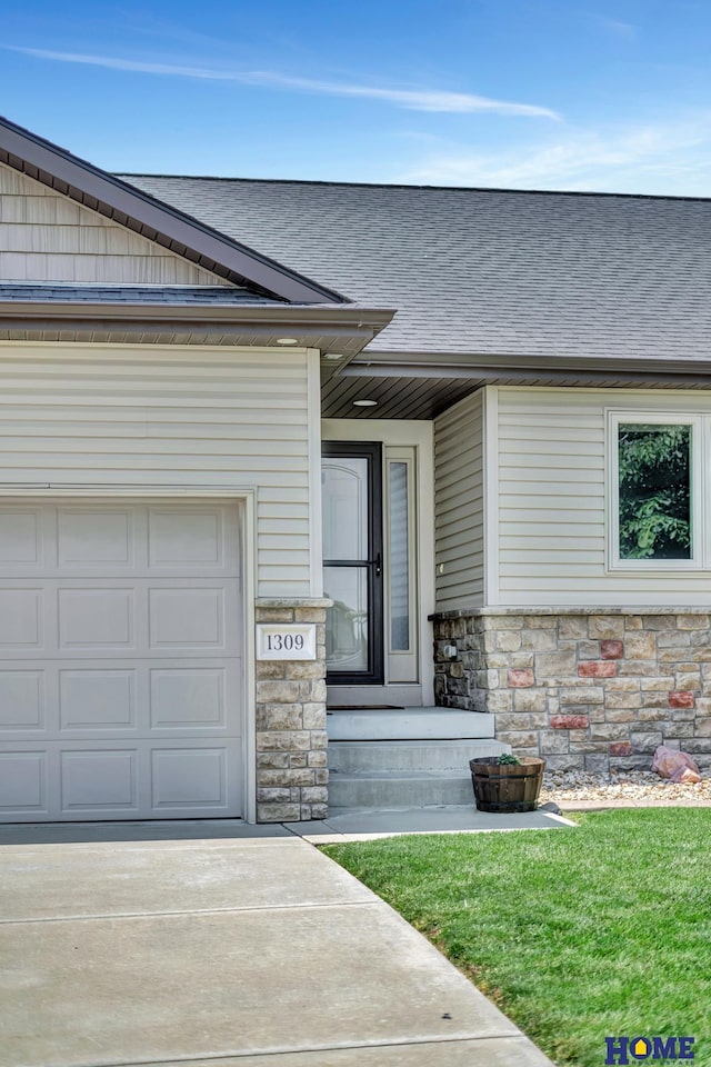 1309 Ridge Rd, Hickman, NE 68372 - view of exterior entry with stone siding, a shingled roof, concrete driveway, and a yard