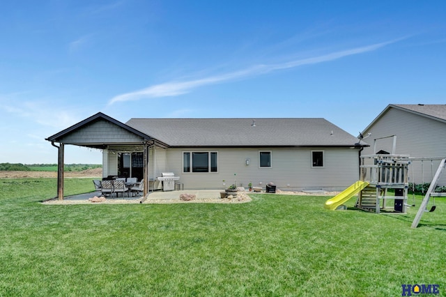 1309 Ridge Rd, Hickman, NE 68372 - back of property featuring a playground, a patio area, a lawn, and a shingled roof
