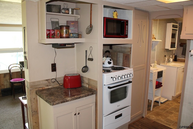 23809 F Plz Unit 9, Waterloo, NE 68069 - kitchen featuring white electric stove, open shelves, white cabinets, dark countertops, and a sink