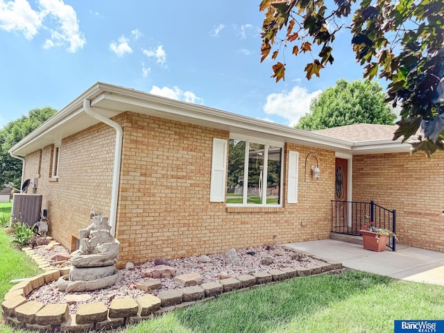 1881 Meadow Ln, Seward, NE 68434 - view of exterior entry featuring brick siding, a yard, and central AC unit