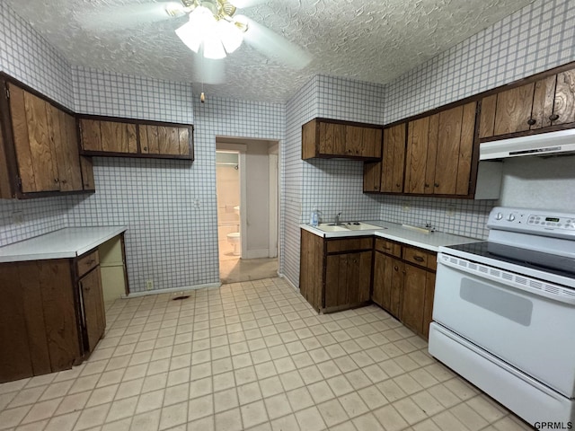 6035 Woolworth Ave, Omaha, NE 68106 - kitchen featuring white range with electric stovetop, under cabinet range hood, light countertops, wallpapered walls, and a ceiling fan