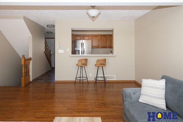 6207 Benjamin Pl, Lincoln, NE 68516 - kitchen with stainless steel fridge, brown cabinetry, wood finished floors, a kitchen breakfast bar, and baseboards