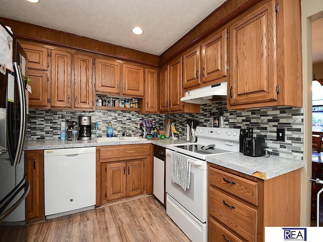 2103 Randall Dr, Bellevue, NE 68005 - kitchen featuring white appliances, under cabinet range hood, a sink, brown cabinetry, and recessed lighting
