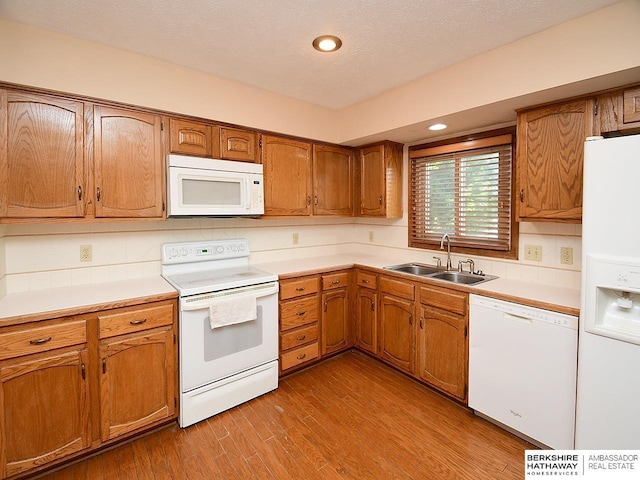 15211 Pasadena Ave, Omaha, NE 68144 - kitchen with white appliances, brown cabinetry, light wood-type flooring, light countertops, and recessed lighting