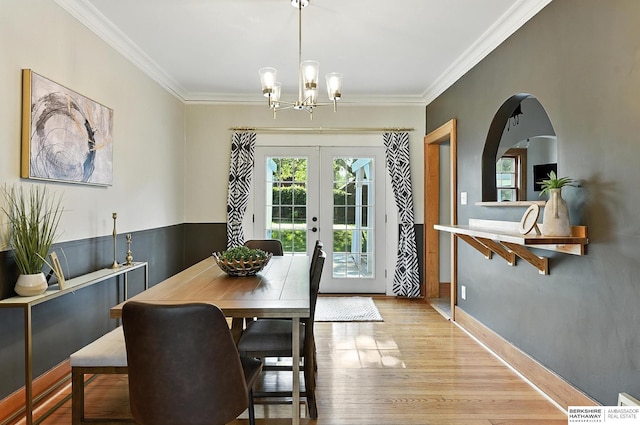 2311 N 51st St, Omaha, NE 68104 - dining room with ornamental molding, a chandelier, arched walkways, french doors, and light wood finished floors