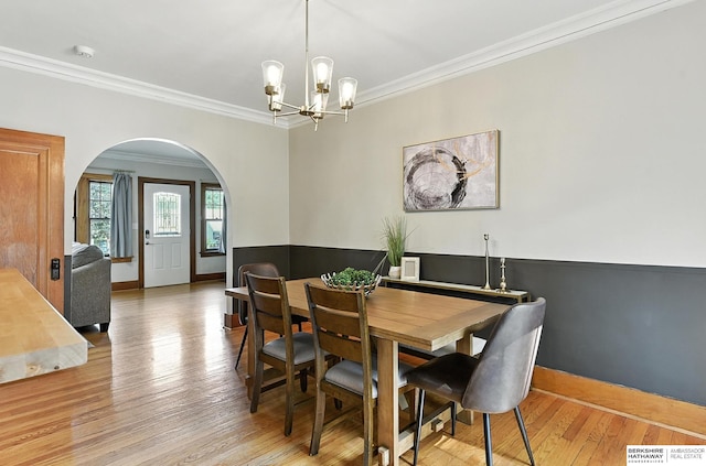 2311 N 51st St, Omaha, NE 68104 - dining area with arched walkways, light wood finished floors, crown molding, and a chandelier