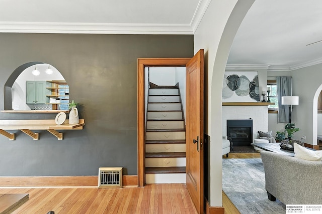2311 N 51st St, Omaha, NE 68104 - staircase with wood finished floors, a glass covered fireplace, ornamental molding, and arched walkways