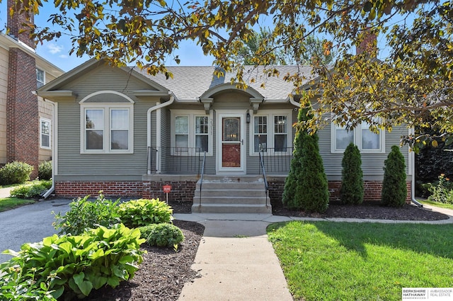 2311 N 51st St, Omaha, NE 68104 - bungalow-style house with a porch, roof with shingles, a chimney, and a front yard