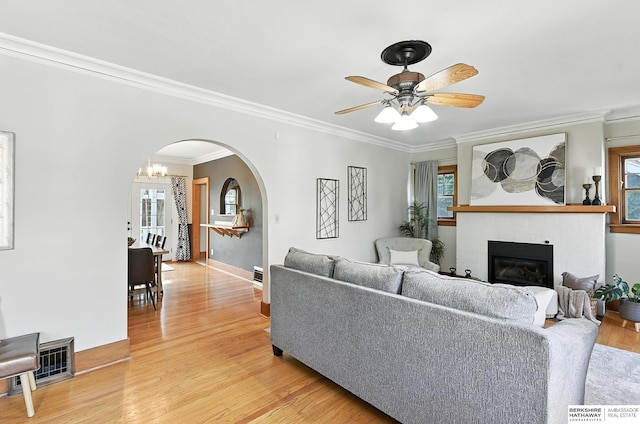 2311 N 51st St, Omaha, NE 68104 - living area featuring arched walkways, a glass covered fireplace, crown molding, light wood-style floors, and healthy amount of natural light