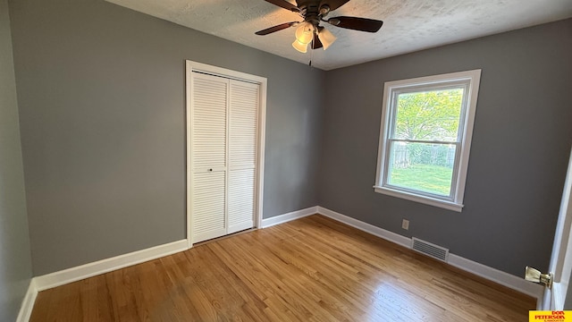 1506 E 1st St, Fremont, NE 68025 - unfurnished bedroom with baseboards, a closet, light wood-style floors, ceiling fan, and a textured ceiling