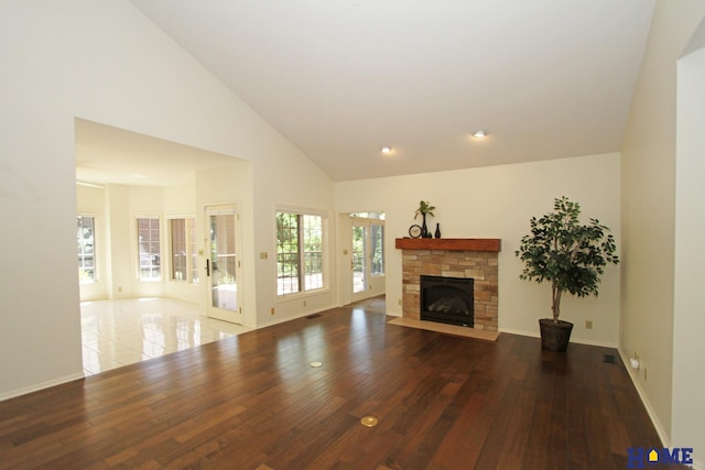 6427 Lone Tree Dr, Lincoln, NE 68512 - unfurnished living room featuring a stone fireplace, hardwood / wood-style floors, high vaulted ceiling, baseboards, and recessed lighting