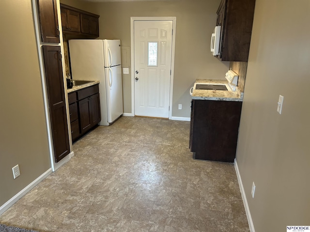 6048 P St, Omaha, NE 68117 - kitchen with dark brown cabinets, white appliances, baseboards, and light stone counters