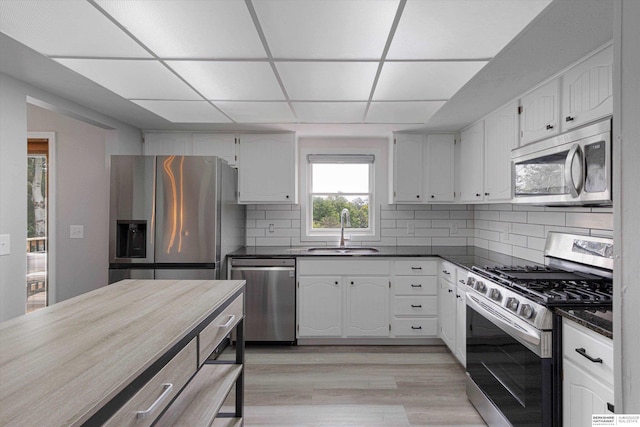 2629 N 129th Cir, Omaha, NE 68164 - kitchen featuring stainless steel appliances, a sink, dark countertops, tasteful backsplash, and white cabinets