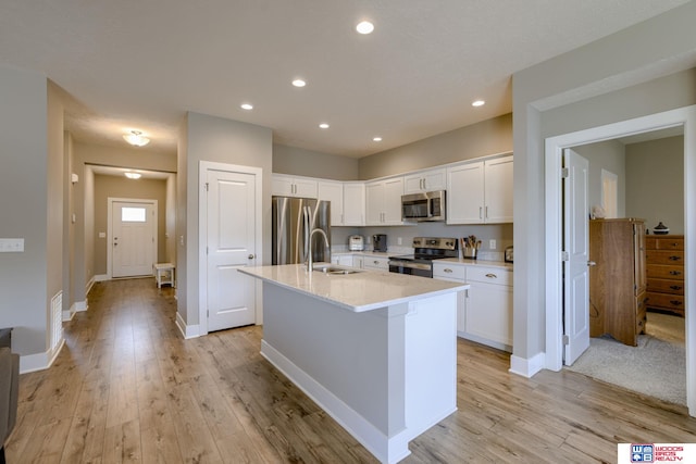 1637 W Avalanche Rd, Lincoln, NE 68521 - kitchen featuring appliances with stainless steel finishes, light wood finished floors, a kitchen island with sink, white cabinetry, and recessed lighting
