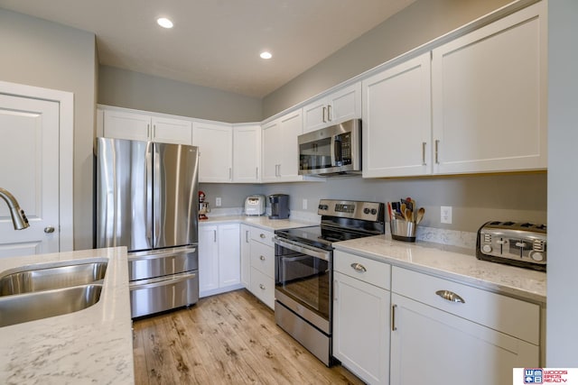 1637 W Avalanche Rd, Lincoln, NE 68521 - kitchen with appliances with stainless steel finishes, white cabinetry, light wood-style floors, recessed lighting, and light stone counters
