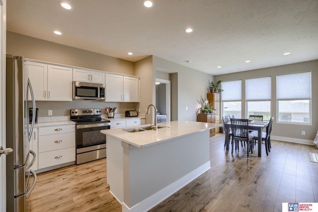 1637 W Avalanche Rd, Lincoln, NE 68521 - kitchen featuring stainless steel appliances, light wood-style floors, white cabinetry, a kitchen island with sink, and recessed lighting