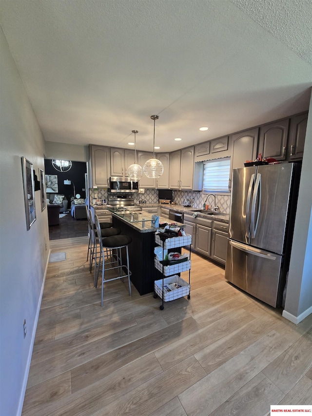 1807 S 16th Circle Dr, Beatrice, NE 68310 - kitchen with stainless steel appliances, a sink, a breakfast bar, decorative backsplash, and baseboards