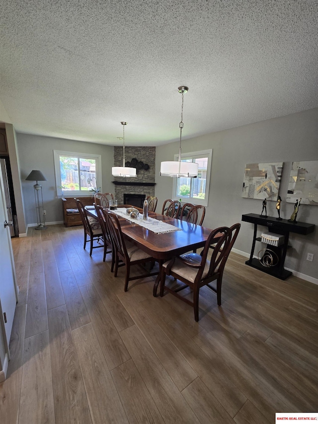 1807 S 16th Circle Dr, Beatrice, NE 68310 - dining space featuring wood finished floors, a textured ceiling, a fireplace, and baseboards