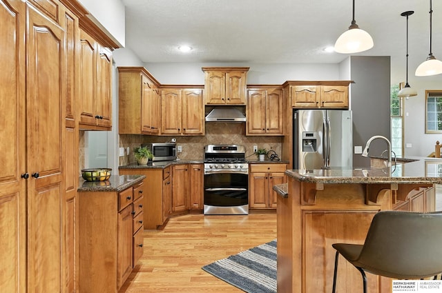 5418 S 165th St, Omaha, NE 68135 - kitchen featuring stainless steel appliances, under cabinet range hood, light wood finished floors, a breakfast bar area, and brown cabinets