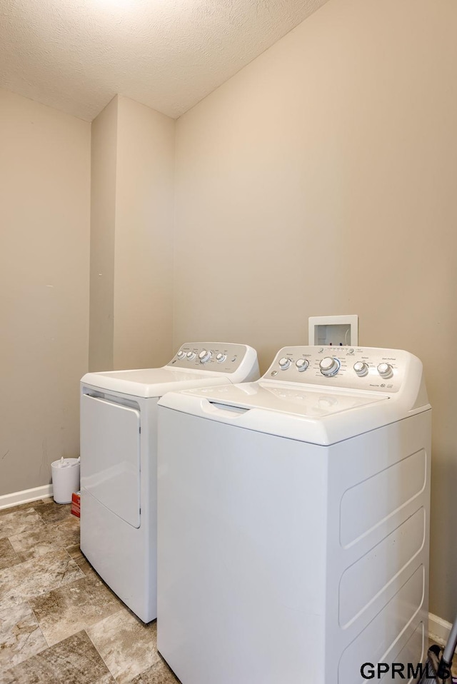 7810 S 184th Ave, Omaha, NE 68136 - washroom featuring washing machine and clothes dryer, baseboards, stone finish flooring, and a textured ceiling