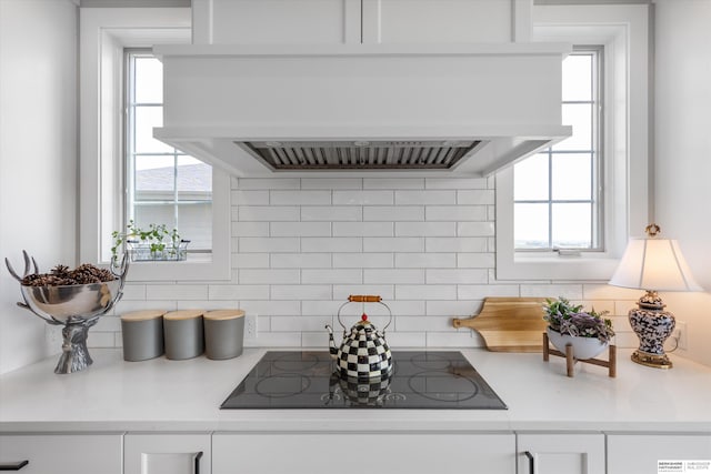 3307 S 209th St, Omaha, NE 68022 - kitchen with ventilation hood, black electric stovetop, white cabinetry, decorative backsplash, and light countertops