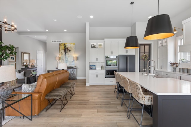 3307 S 209th St, Omaha, NE 68022 - kitchen with stainless steel double oven, high end refrigerator, a breakfast bar area, light countertops, and light wood finished floors