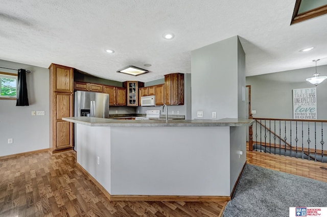1035 Primrose Ln, Hickman, NE 68372 - kitchen featuring white microwave, stainless steel refrigerator with ice dispenser, brown cabinetry, glass insert cabinets, and a peninsula