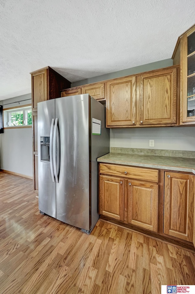 1035 Primrose Ln, Hickman, NE 68372 - kitchen featuring stainless steel refrigerator with ice dispenser, light wood-type flooring, a textured ceiling, brown cabinetry, and light countertops