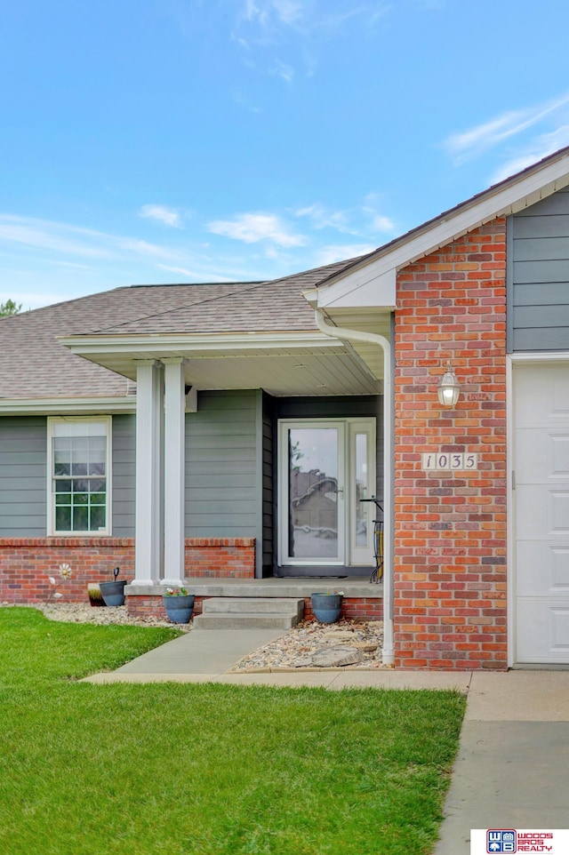 1035 Primrose Ln, Hickman, NE 68372 - entrance to property featuring brick siding, roof with shingles, a yard, covered porch, and a garage