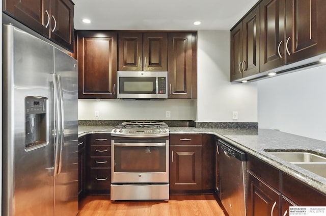 3200 Farnam Ct Unit 3409, Omaha, NE 68131 - kitchen featuring appliances with stainless steel finishes, light wood-style flooring, dark brown cabinetry, recessed lighting, and dark stone counters